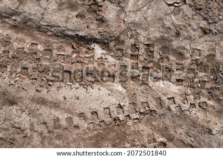 Motorcycle tire tracks on a muddy trail. Tire tracks on a wet muddy road, abstract background, texture material. Tire track on clay, sand driving, off road