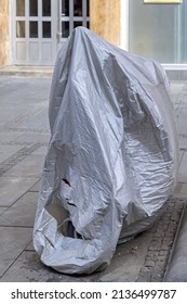 Motorcycle Under Silver Tarp Cover Parked At Street Winter