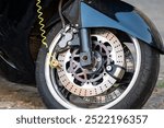 A motorcycle wheel with a lock attached to its disc brake.