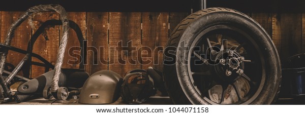 Motorcycle wheel on the floor with workshop\
tools, vintage garage, with blank copy\
space\
