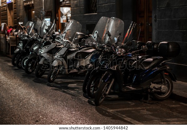 Motorcycles and scooters in the night\
Parking lot | FLORENCE, ITALY - 14 SEPTEMBER\
2018.