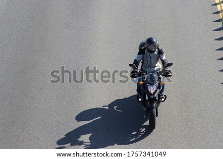 A motorcyclist in a helmet with a closed face rides on the road.