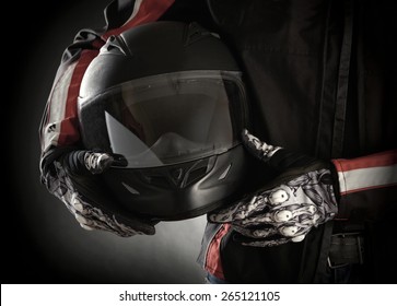 Motorcyclist With Helmet In His Hands. Dark Background