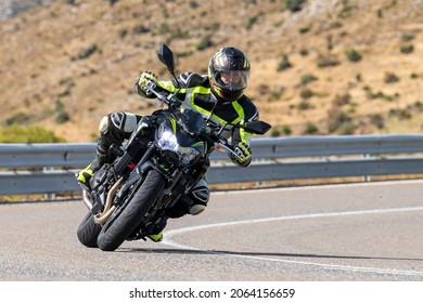 motorcyclist lying down with his motorcycle on the curve of the road. Photo taken during the month of September 2020, in the port of Navalmoral, province of Avila, Spain