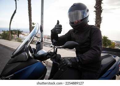 A motorcyclist on his motorcycle gives the thumbs up, happy motorcycle enthusiast.
