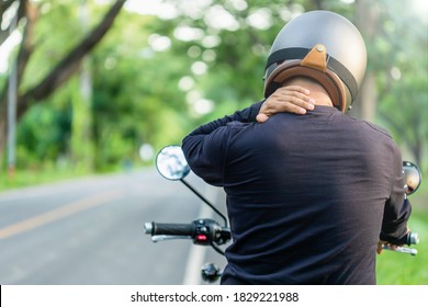 Motorradfahrer mit Schmerz oder müdem Konzept: Man-Fahrer berühren sich an Nacken oder Schulter und fühlen sich müde nach langen Motorrädern. Outdoor Shooting auf der Straße mit Kopienraum