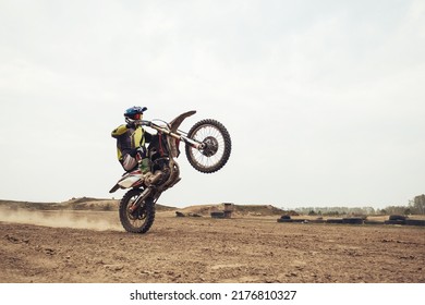 Motorcyclist Wearing Helmet And Moto Gear Riding On Rear Wheel On Motocross Dirt Bike At Moto Drome