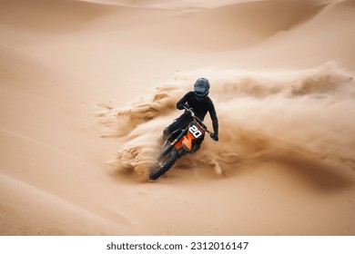 Motorcyclists at the dirt bike going fast at the dune