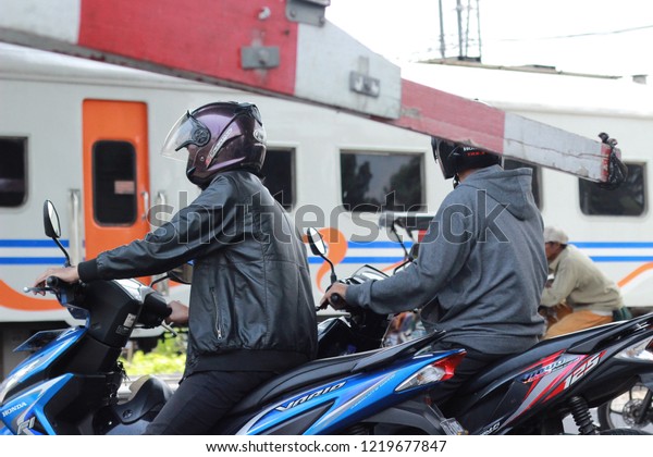 motorcyclists waiting for\
the train pass on the train\'s doorstop, Bandung city, West Java -\
September 6, 2018