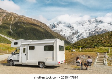 Motorhome camper van RV road trip on New Zealand. Couple on travel vacation adventure. Tourists looking at view of Aoraki Mount Cook National park and mountains on pit stop next to their rental car