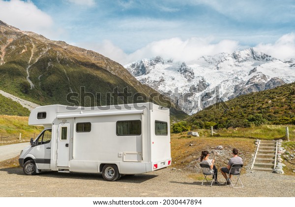 Motorhome camper van RV road trip on New Zealand.\
Couple on travel vacation adventure. Tourists looking at view of\
Aoraki Mount Cook National park and mountains on pit stop next to\
their rental car