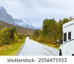 A motorhome parked by the road in the autumn landscape of Senja Island, Norway, with fjords and mountains.