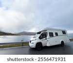 A motorhome parked by the road in the autumn landscape of Senja Island, Norway, with fjords and mountains.