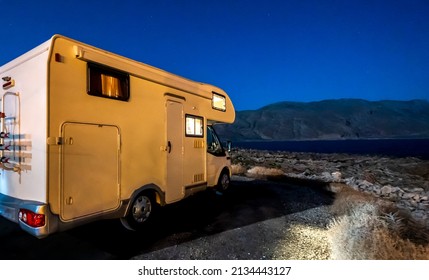 Motorhome RV Parked Under Stars On A Pier By The Sea, Crete, Greece. Travelers With Camper van Are Resting Overnight On An Active Family Vacation In Kissamos, Crete, Greece.