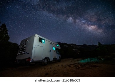 Motorhome RV Parked Under Stars On A Pier By The Sea, Crete, Greece. Travelers With Camper Van Are Resting Overnight Under Milky Way On An Active Family Vacation, Crete, Greece.