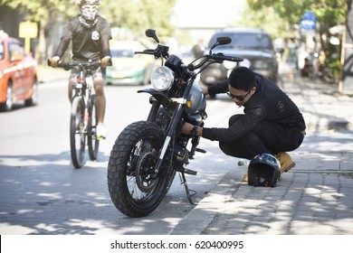 A motorist having problems with his motorcycle during a trip. Serious young man repairing his motorcycle during trip. - Powered by Shutterstock