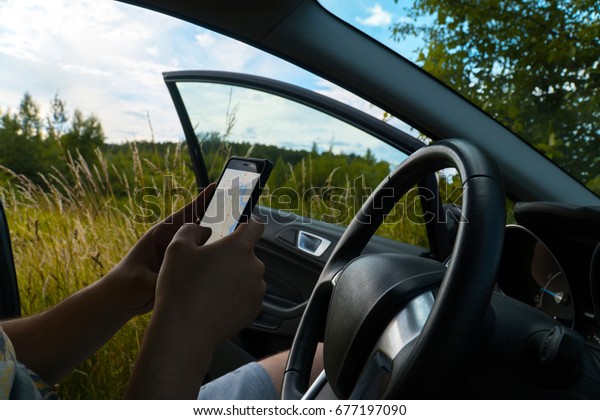 Motorist lost\
his way. The man is trying to find the way on the navigator in the\
mobile phone. Field in the\
background.