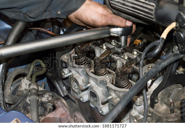 The motorist tightens the bolts on the head of the\
block of a three-cylinder gasoline internal combustion engine using\
a torque wrench