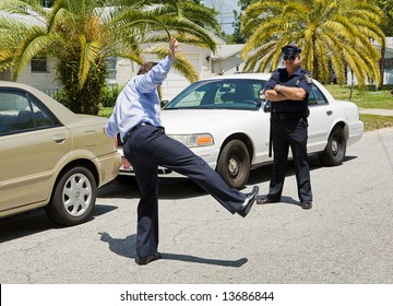 Motorist Trying To Walk A Straight Line While A Police Officer Looks On.