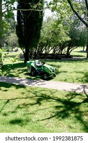 Motorized Large Green Lawn Mower Stands Near The Trees In The Park