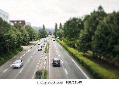 Motorway In Germany With Speedy Cars Surrounded By Green Backgrounds - Tilt Shift Lens Used To Accent Motorway And To Emphasize The Speed Vision