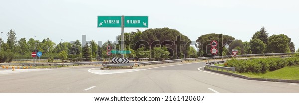 motorway\
junction with the Italian indications for the city of VENICE on the\
LEFT or MILAN if you turn RIGHT without\
cars