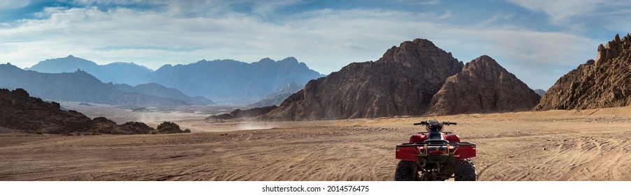 Moto-safari in a stone desert at sunset. Mountain landscape with off-road vehicles driving on a dust dirt road. Active leisure for tourists in Sharm el-Sheikh resorts, Egypt.