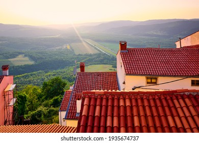 Motovun Croatia. View With High Hill At Green Lowland. Red Tegular Roof With Chimney. Picturesque Landscape. Sunset Over Forest And Background.