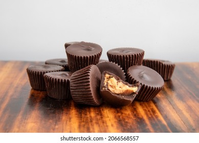 A Mound Of Chocolate Peanut Butter Cups On A Dark Wooden Table