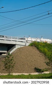 A mound of pebbles at the foot of an automobile overpass. Concrete car overpass in the city center. Concrete overpass with massive concrete supports.