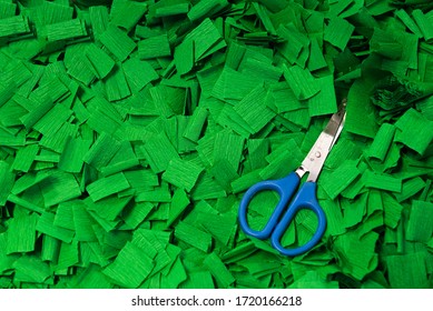 Mound Of Vibrant Green Squares Of Crepe Paper With Pair Of Blue-handled Scissors With Measurement In Centimetres On Blades