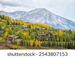 Mount Crested Butte, Colorado village town in autumn at Rocky mountains by apartment buildings, condos houses cityscape and turning colors