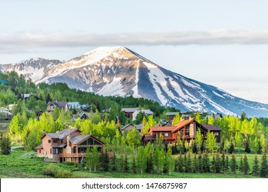 Mount Crested Butte, Colorado village in summer with colorful sunrise by wooden lodging houses on hills with green trees