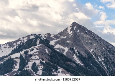 Mount Crested Butte Snow Mountain In Summer Closeup Of Point Peak With Cloudy Sky And Pine Trees