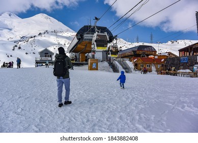 Mount Elbrus, Kabardino-Balkaria April 2019: Photo Of A Young Man With A Child At The Mir Station Of The Highest Cable Car In Europe, Elbrus. Russia.