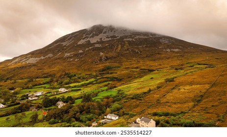 Mount Errigal in Donegal Ireland - A stunning view of a misty mountain with lush greenery and charming cottages nestled peacefully below - Powered by Shutterstock