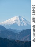 Mount Fuji, panoramic view on the snow-capped peak of Mt Fuji between the mountains at the Mount Takao viewpoint at daytime with blue sky in Japan with space for text.