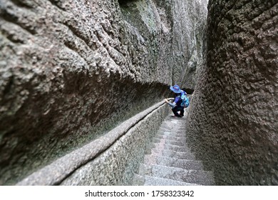 Mount Huangshan, Anhui, China - June 16, 2019: A man is going down the stairs between narrow cliffs
