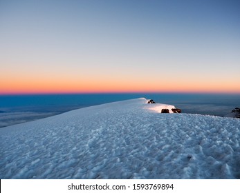 Mount Kilimanjaro And Meru In The Tanzanian Serengiti As Dawn Breaks Above The Clouds. Hikers Make The Slow Trek To The Summit For Sunrise