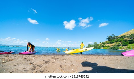 MOUNT MAUNGANUI NEW ZEALAND - FEBRUARY 10:  Children Carrying Colorful Paddle Boards Developing Water Confidence And Skills By Surf Lifesaving Club February 10 2019 Mount Maunganui New Zealand