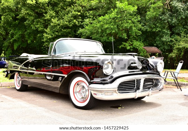 Mount Pleasant,\
Wisconsin / USA - July, 21, 2019: A beautiful straight black 1956\
Oldsmobile 88 Convertible with the top down at the Quarry Lake Park\
Car Show in Wisconsin. 