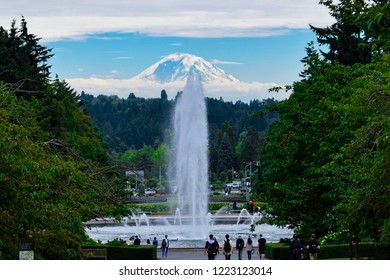 Mount Rainier As Seen From The University Of Washington In Seattle, Washington With A Fountain In View And People Walking By