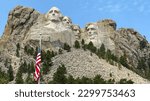 mount rushmore and american flag against a blue sky