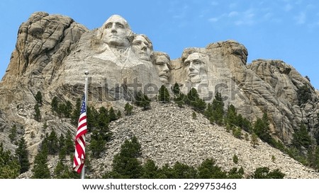 mount rushmore and american flag against a blue sky