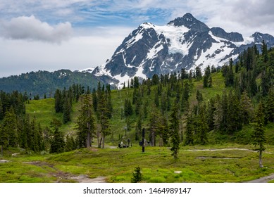 Mount Shuksan in the Pacific Northwest Cascade Mountain range rises under a blue sky with some clouds.  In the foreground is an unused ski lift waiting for its seasonal visitors. - Shutterstock ID 1464989147