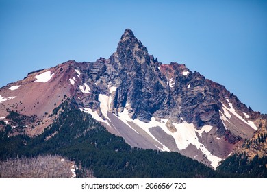 Mount Washington In Oregon As Seen On A Sunny Summer Day. Jagged Mountain Peak With Snow And Dense Treeline Below, Blue Sky Above.