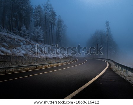 Mountain asphalt road during foggy conditions,trees covered with rime, white line. Bad weather. Jeseniky mountains,Czech Republic.