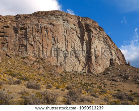 Mountain Bathed in Sunlight. White Clouds. Blue Sky. Steep Mountainside. Dry Grass Field at the Bottom of Mountain Slope. Landscape Without People. Desert Mountain.