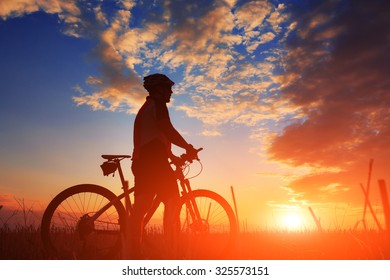 Mountain Bicycle Rider On The Hill With Sunrise Background