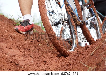 A mountain bike cyclist walking through a muddy road / Cycling in wet condition concept   